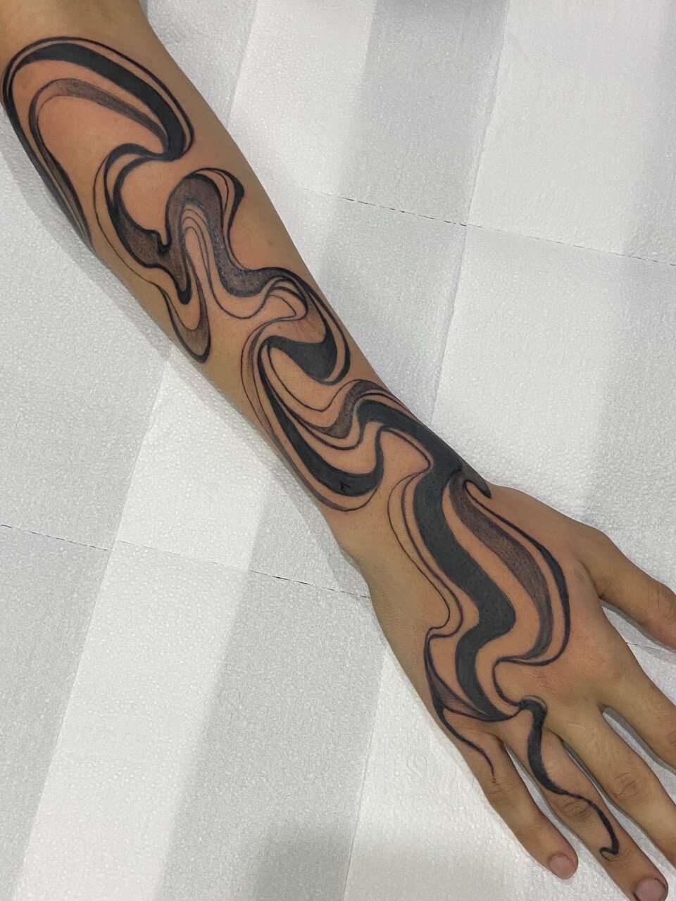 Tatuagem blackwork abstrata no braço e mão